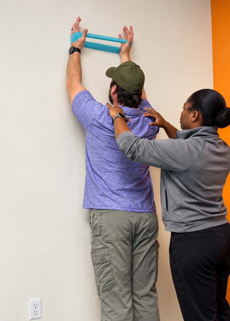 Dr. Mishka Spencer guiding a patient through a shoulder movement exercise
